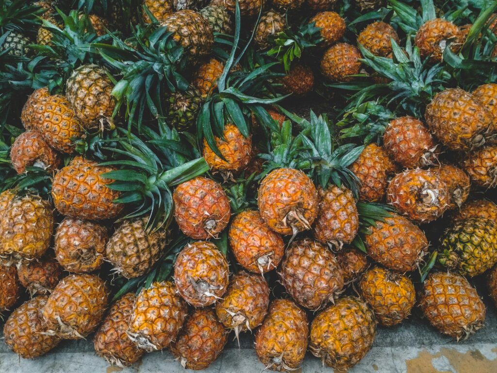 A vibrant display of ripe pineapples at a tropical outdoor market, showcasing freshness.