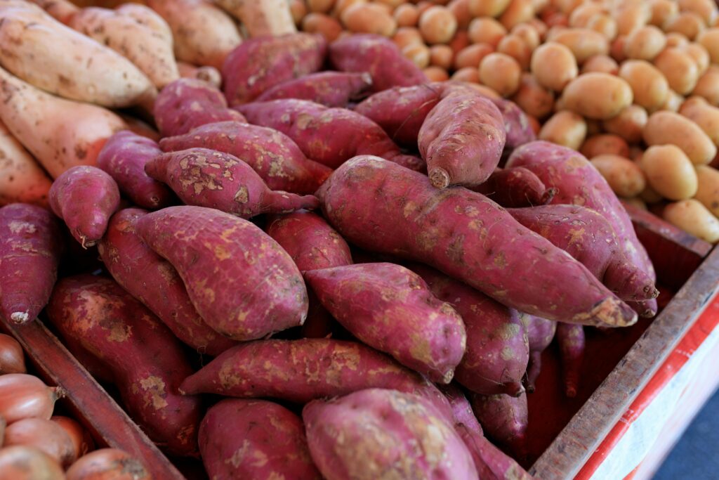 A vibrant selection of fresh sweet potatoes at a local market display highlighting their rich colors and textures.