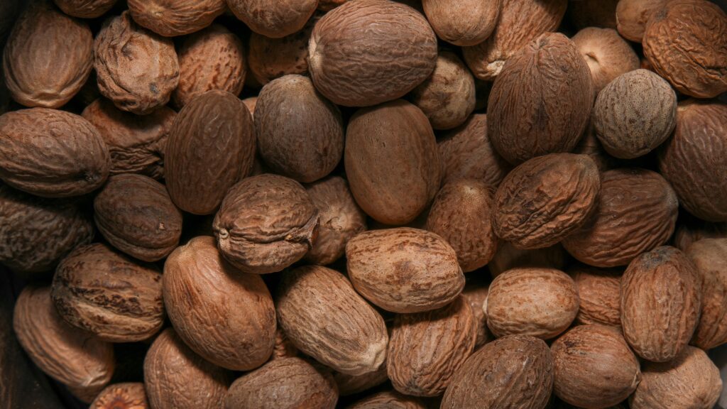 High-quality close-up image of whole nutmeg seeds with textured shells.