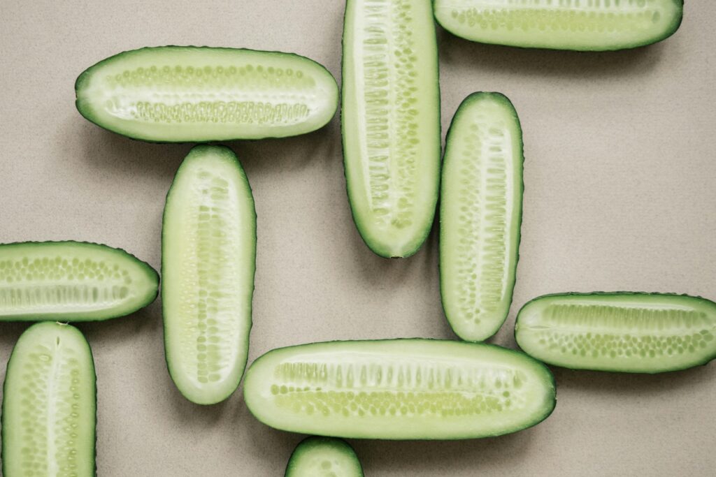 Top view of fresh sliced cucumbers arranged on a neutral background, showcasing their vibrant freshness.
