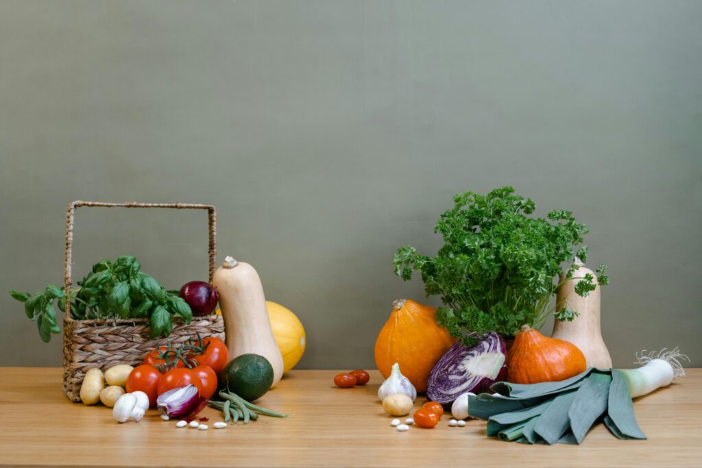 A variety of fresh vegetables including squash, tomatoes, and greens arranged on a wooden table.